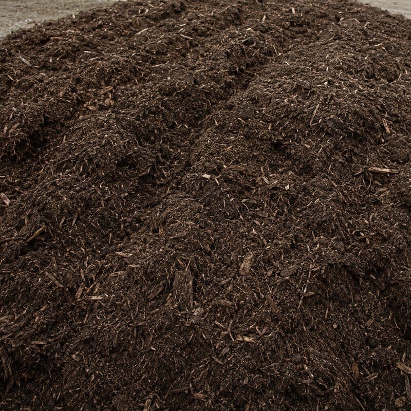 El mismo material en descomposición avanzada: predominan los marrones, la estructura vegetal apenas se distingue y quedan astillas de madera visibles.